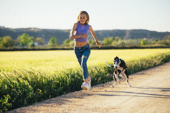 Beautiful young blonde woman running in the field with her greyhound dog. - Stock Photo - Images