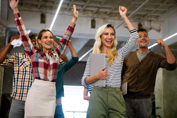 Happy young successful business team celebrating a triumph with arms up in startup office. - Stock Photo - Images