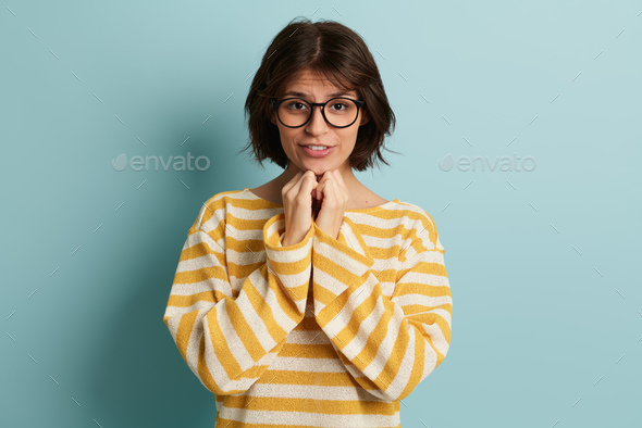 Worried young ethnic lady with hands at chin looking at camera - Stock Photo - Images