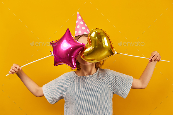 Cheerful, positive ten years birthday girl in party hat - Stock Photo - Images