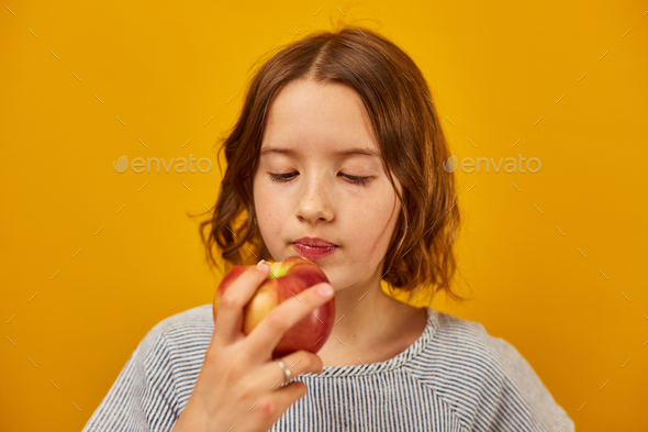 Pretty teen girl, child eat, bites a fresh red apple - Stock Photo - Images