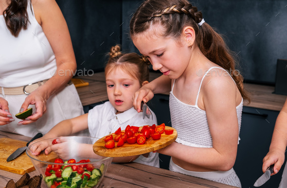 A little girl is preparing a vegetarian salad  - Stock Photo - Images