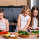 Three cute little sisters preparing vegetarian salad at the kitchen. - PhotoDune Item for Sale