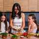 A young mother teaches her daughters to cook a vegetarian salad in the kitchen at home.  - PhotoDune Item for Sale