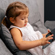 Cute little girl sitting on sofa and using tablet. - PhotoDune Item for Sale