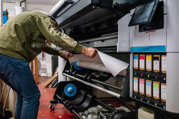 Anonymous man printing banner in printing office