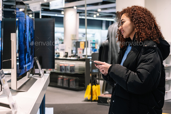 Black woman looking at TV screen in shop