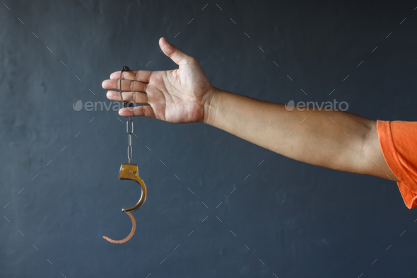 Hand of prisoner holding opened handcuffs. Free from jail or freedom concept - Stock Photo - Images