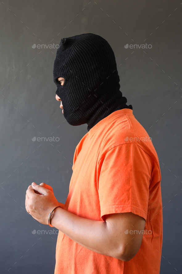 Side view of a prisoner in orange t-shirt wearing handcuff  - Stock Photo - Images