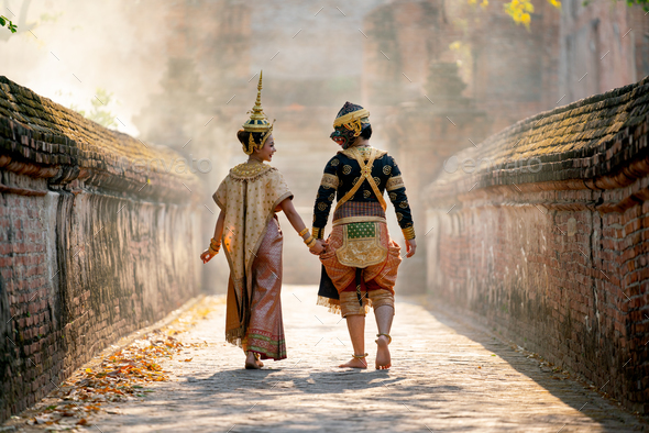 Beautiful Asian woman wear Thai traditional dress action of walking together with Thai classic mask