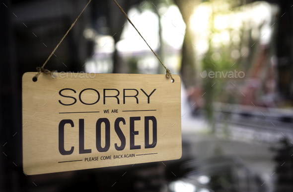 The sign is closed. Hanging on the glass at the front door, the sign message on a wooden, please com