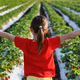 Little girl stands with her back against the background of a strawberry field and gives a thumbs up. - PhotoDune Item for Sale