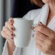 Relaxed Asian woman wearing bath robe drinking coffee in hotel room in morning - PhotoDune Item for Sale