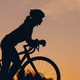Silhouette of a woman riding a bike during a sport cycling race on a sunset - PhotoDune Item for Sale