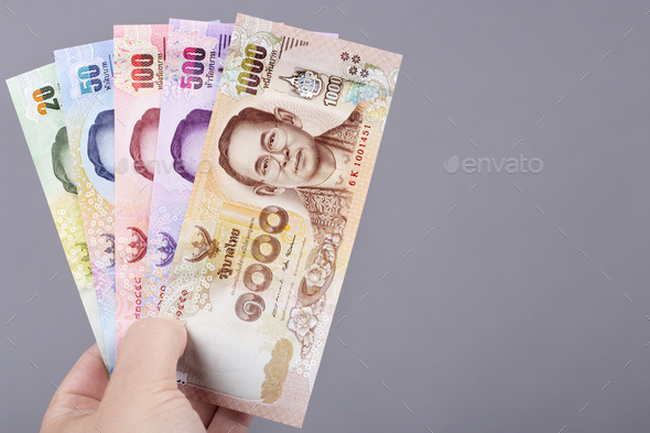Thai money in the hand on a gray background - Stock Photo - Images