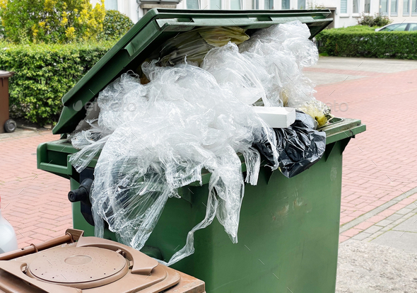 green garbage container bin overflowing with plastic packaging waste - Stock Photo - Images