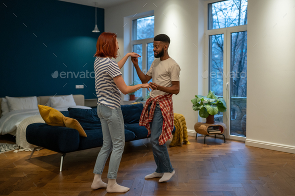 Romantic interracial young family couple wife and husband dancing to music together at home - Stock Photo - Images