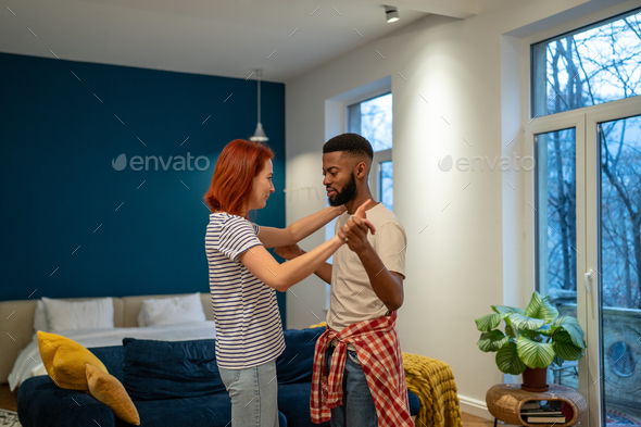 Joyful young diverse married couple dancing having fun in living room at home - Stock Photo - Images