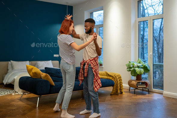 Loving young diverse couple dancing romantic dance in modern bedroom with panoramic windows. - Stock Photo - Images