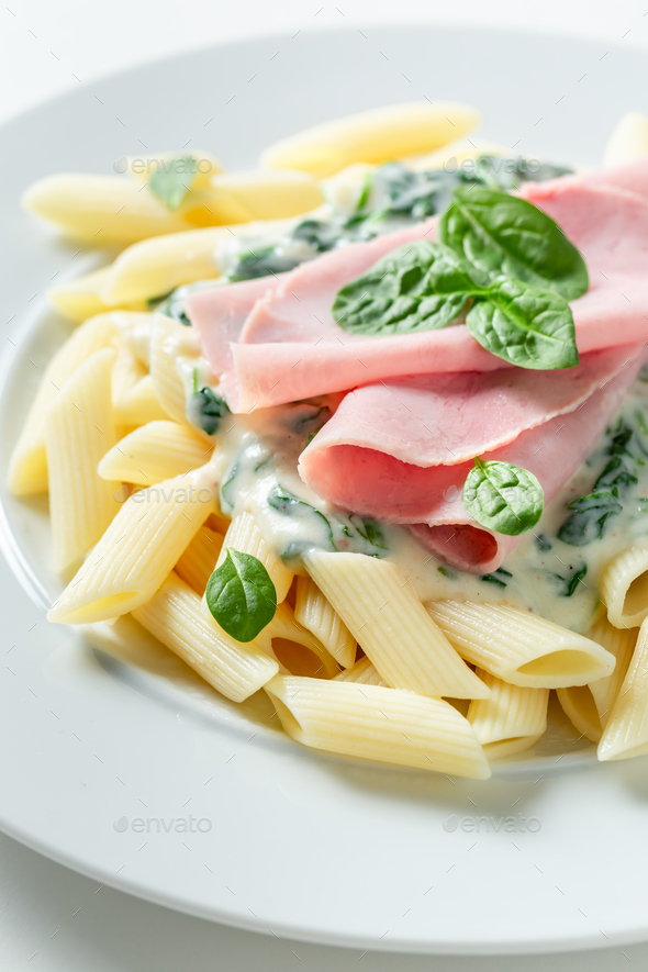 Tasty and homemade penne with spinach and bechamel sauce. - Stock Photo - Images