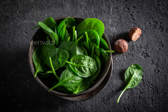 Green spinach leaves and nutmeg in dark bowl - Stock Photo - Images