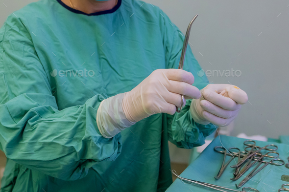 Sterile forceps needle holder was firmly held by surgeon hand encased in medical protective gloves - Stock Photo - Images