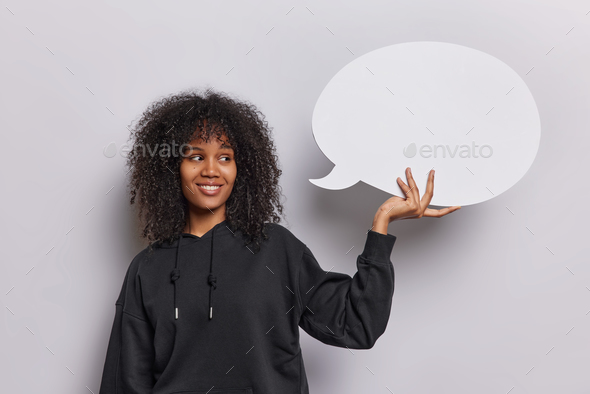 Smiling Afro woman with curly hair holds chat bubble dresse in black casual hoodie suggests empty
