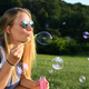 Blonde woman with aviator sunglasses blowing bubbles at golden hour on a warm summer evening. - PhotoDune Item for Sale