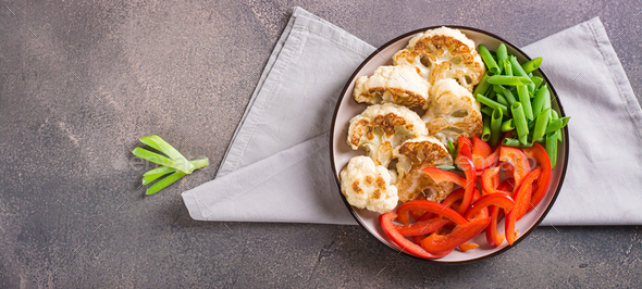 Roasted cauliflower, bell peppers and chives in a veggie bowl top view web banner