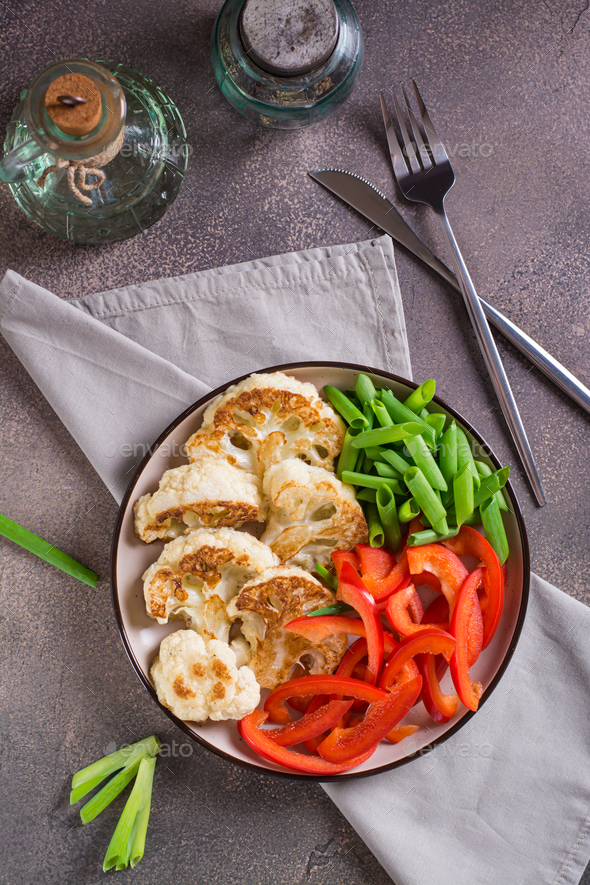 Roasted cauliflower, bell peppers and chives in a veggie bowl top and vertical view