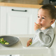 Happy baby sitting in high chair eating fruit in kitchen. Healthy nutrition for kids. Bio carrot as - PhotoDune Item for Sale