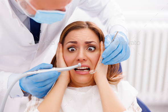 Woman scared while doctor is fixing her tooth at dentist office