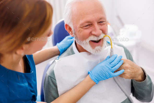Senior man holding saliva suction tube at dentist office