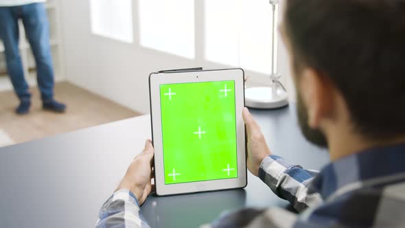 Man Looking at Green Screen Digital Tablet PC in Modern and Bright Apartment alt