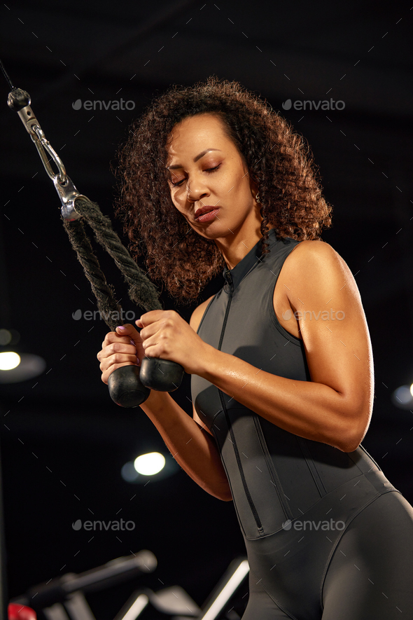 African American woman doing triceps exercises in the gym, close