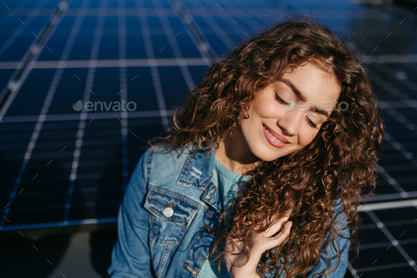 Portrait of young woman on roof with solar panels. - Stock Photo - Images