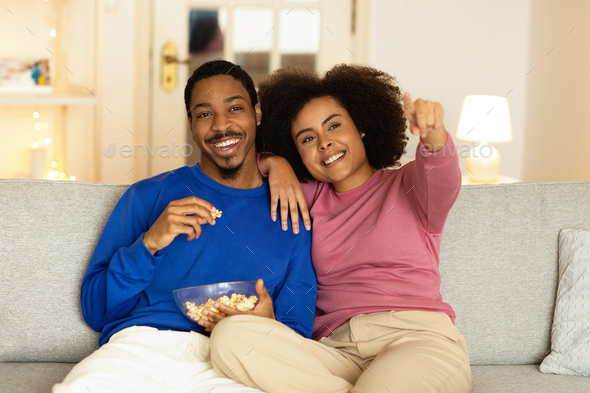 Happy Black Couple With Popcorn Watching Film On TV Indoor