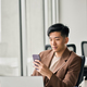 Young busy smiling Asian business man using mobile phone in office. - PhotoDune Item for Sale