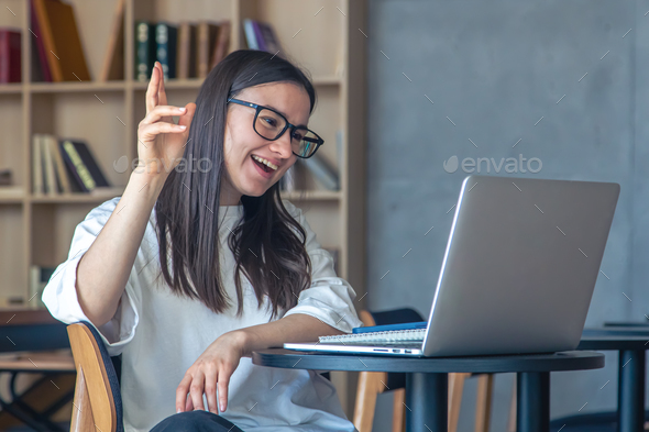 Cheerful young woman in glasses in front of a laptop. - Stock Photo - Images