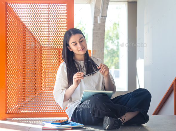 Young woman with glasses and notebook in modern interior, study concept. - Stock Photo - Images