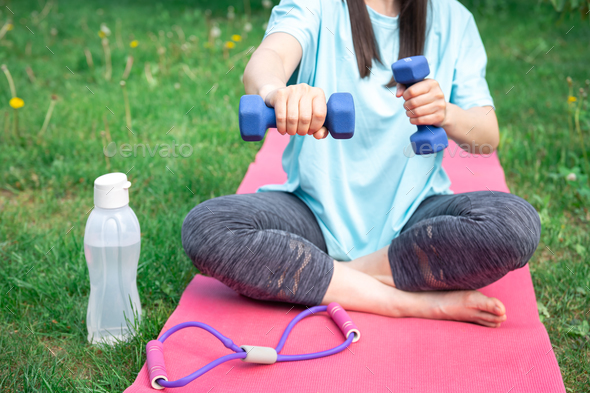 Woman stretching with dumbbells, doing fitness exercises in green park. - Stock Photo - Images