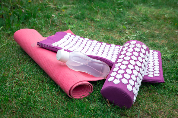 Acupuncture massage mat, water bottle and grass sports mat. - Stock Photo - Images