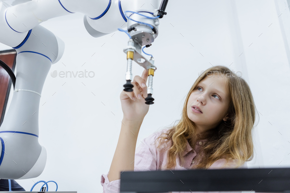 Girl Caucasoid education electronic robotic arm on table at class room.