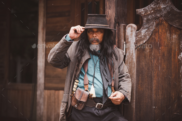 Cowboy posing shooting rifle by gun on hand to show protected weapon wearing cowboy dresser and hat
