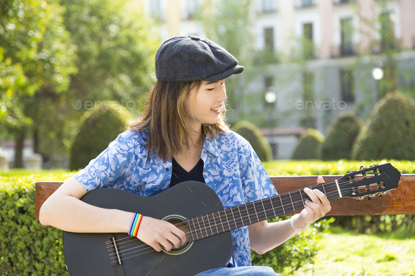 Young musician happily playing guitar in a park - Stock Photo - Images