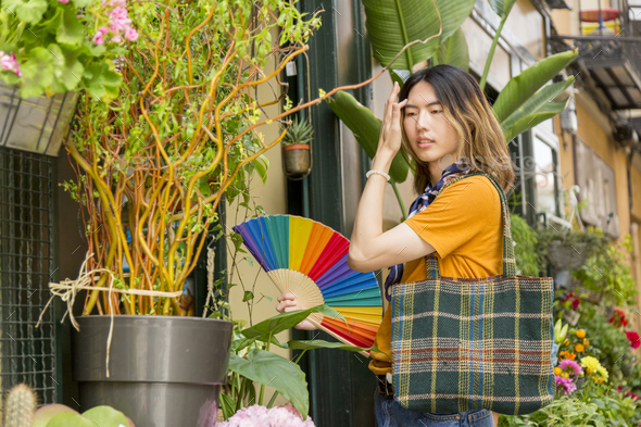 Young gay with multicolored fan entering florist - Stock Photo - Images