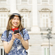 Young with backpack and hat, smiling and happy, using mobile phone - PhotoDune Item for Sale