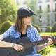 Young musician happily playing guitar in a park - PhotoDune Item for Sale