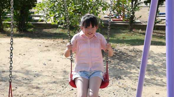 Cute Asian Girl Playing Swing In The Park alt