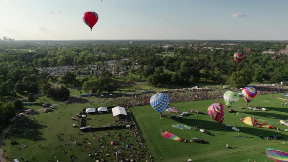 Aerial rise of hot air balloons taking off from Forest Park, St. Louis, starting race. alt